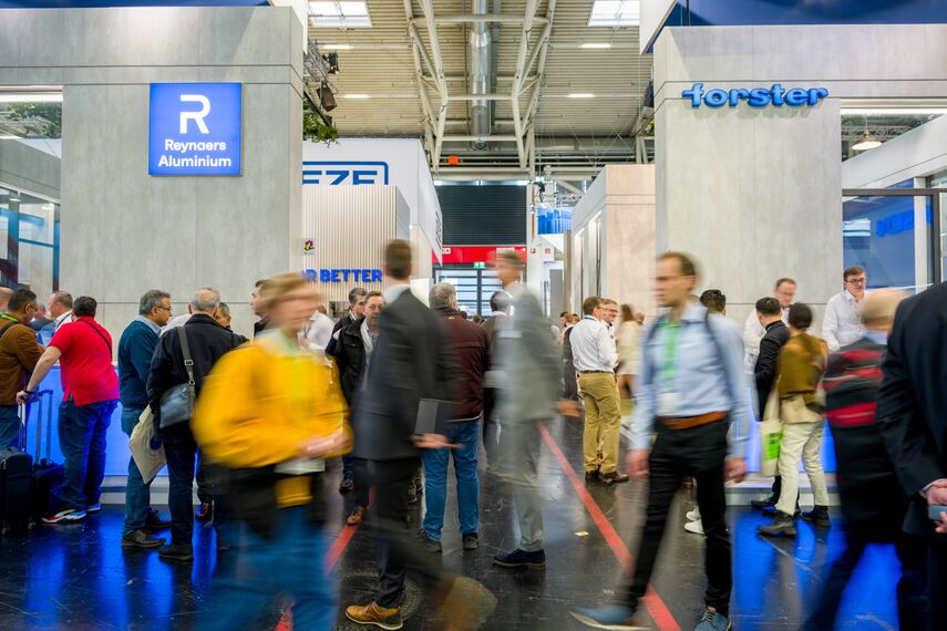 Lidé procházející mezi stánky Reynaers Aluminium a Forster na veletrhu BAU 2023.
