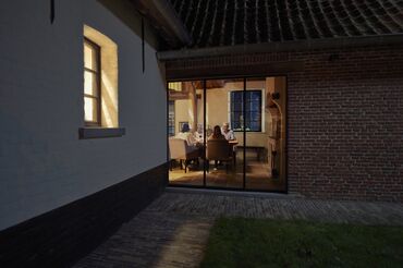 Family sitting at dinner table at night, viewed from outside.