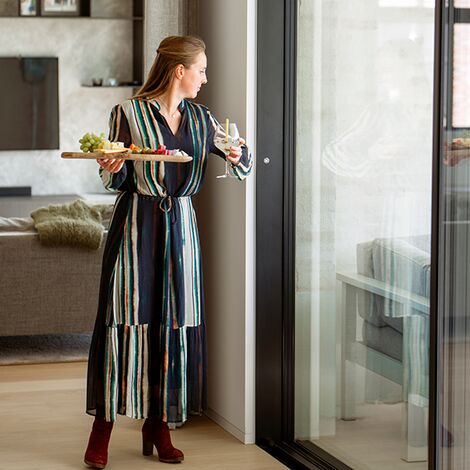 A woman opening a sliding door using comfort motorisation with her hands full