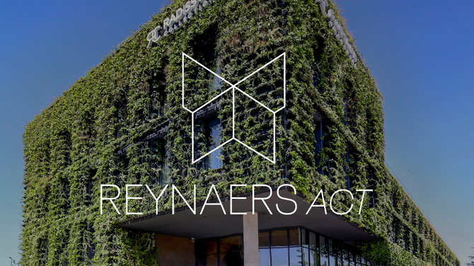 Reynaers Act Logo před zelenou fasádou budovy.