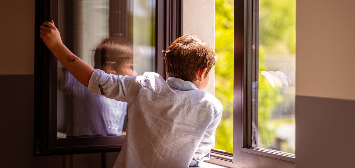 Child looking out of an open window.