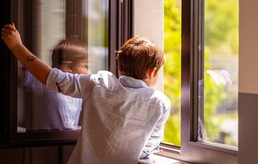 Child looking out of an open window.